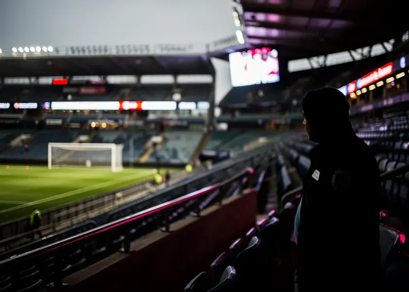 Phil Foden in Manchester City kit during a Premier League match with Pep Guardiola watching from the